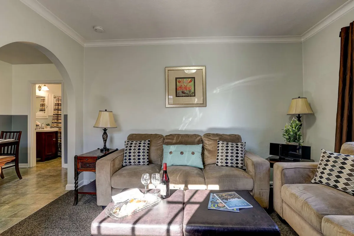 A welcoming living space with a stylish sofa, coffee table, and tasteful artwork, complemented by soft lamp lighting. The room exudes comfort and style, ideal for entertaining guests or enjoying a peaceful moment alone. The arrangement hints at the room's versatility and period charm.