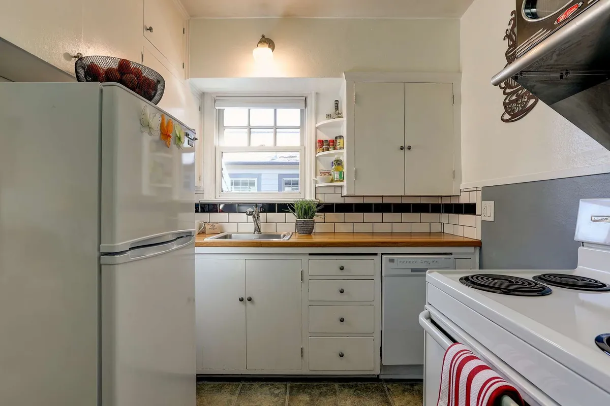 A view of the kitchen sink, refrigerator, stove, and a window that lets in natural light. The layout suggests a well-equipped space designed for cooking, baking, and enjoying family meals.